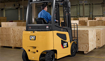 Worker lifting wooden crates with Cat pneumatic forklift